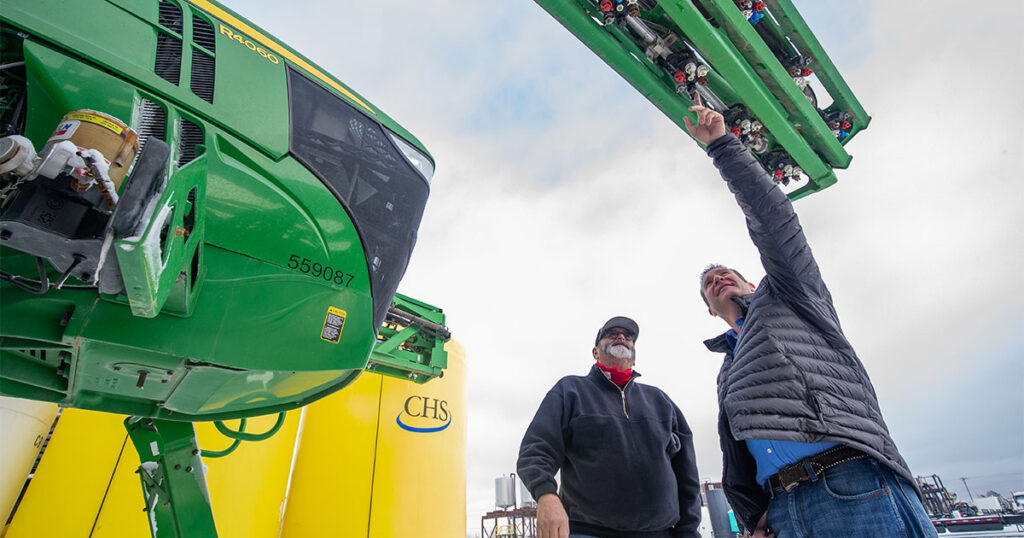 Two man talking by a self-propelled sprayer