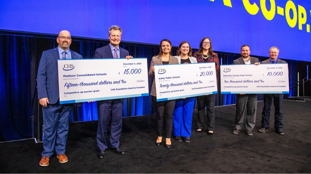 Seven people standing and holding three large checks.