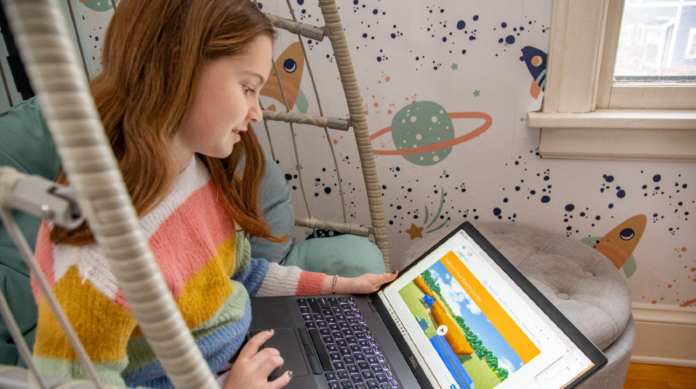 Child playing interactive farming game on laptop.
