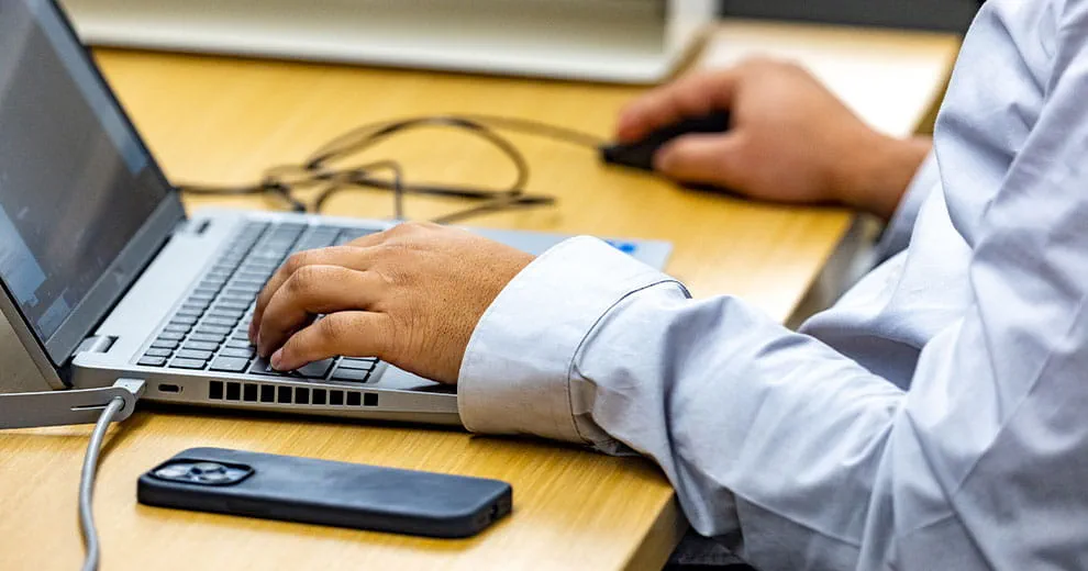 laptop with hand on keyboard in office