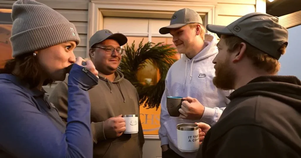 Four people holding mugs near a door.
