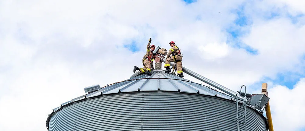 Two firefighters on top of a grain bin