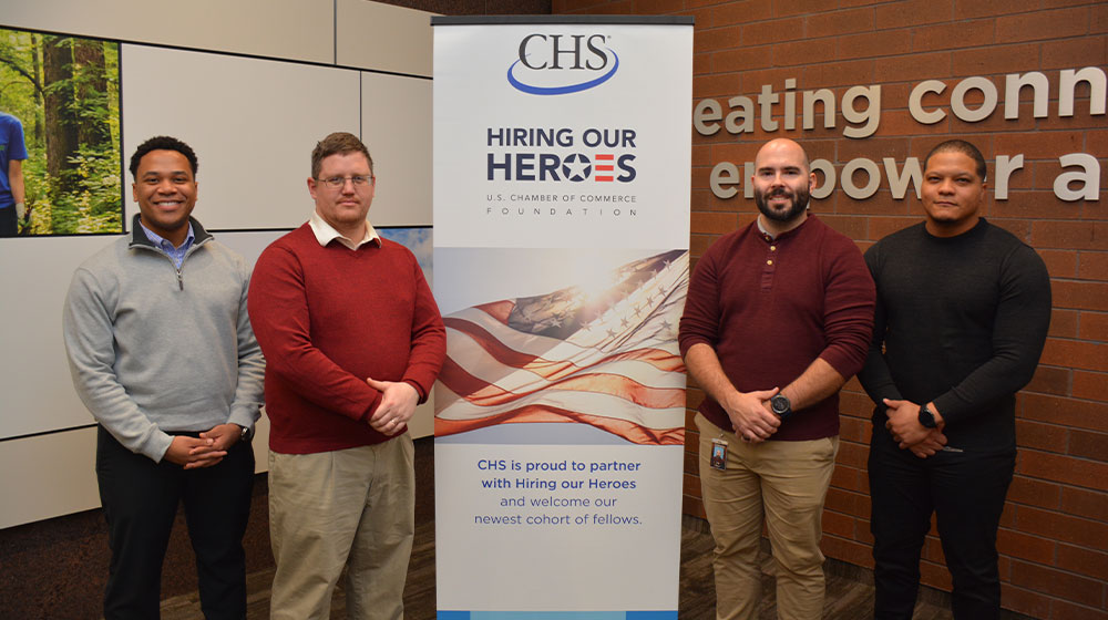 Four men standing next to a CHS popup banner.