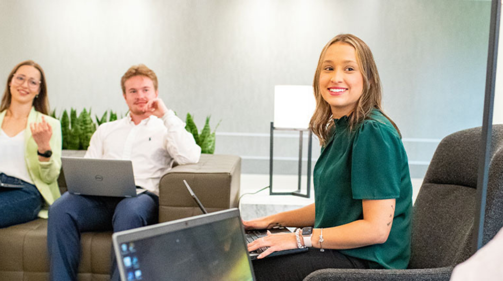 Four interns talking while holding laptops