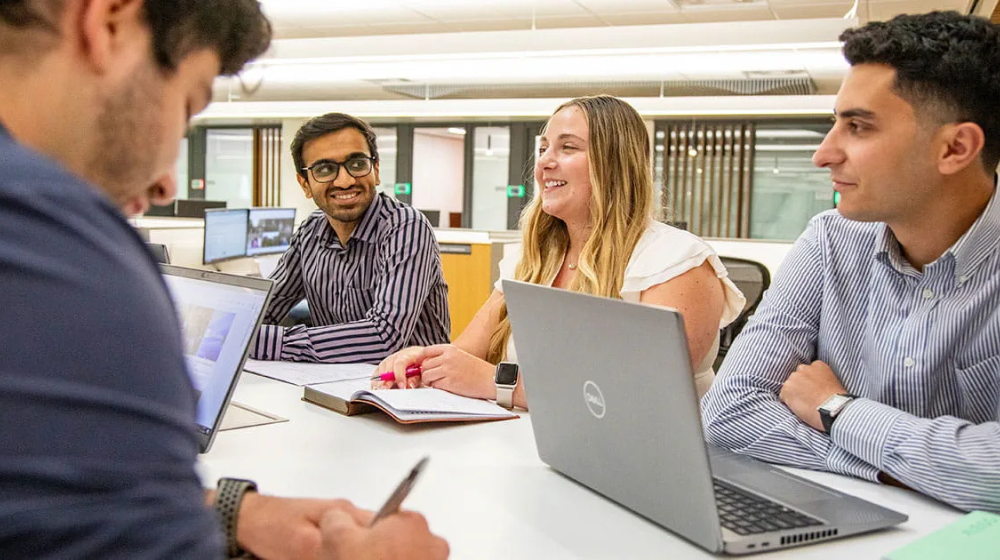 Four interns talking around a table in an office setting