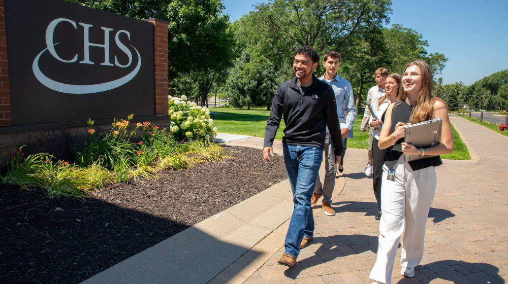 A group of interns walk outside past a CHS sign on the corporate campus