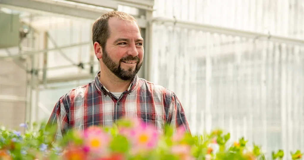 Man standing in a greenhouse with flowers