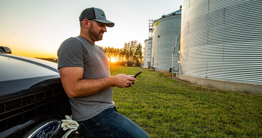 Man on his phone leaning against his truck.