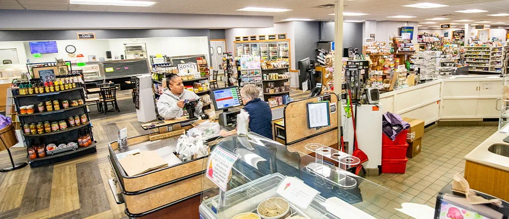 Cashier helping a customer inside of a store that sells food, gifts and more