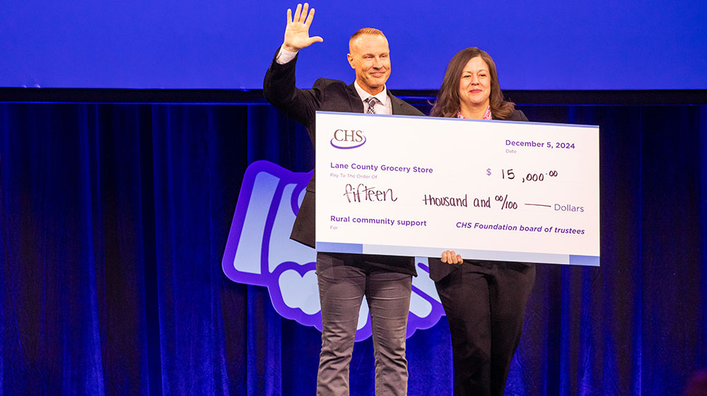 Two people standing on a stage holding a large novelty check.