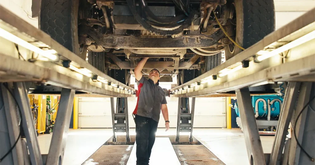man inspecting bottom of vehicle on risers