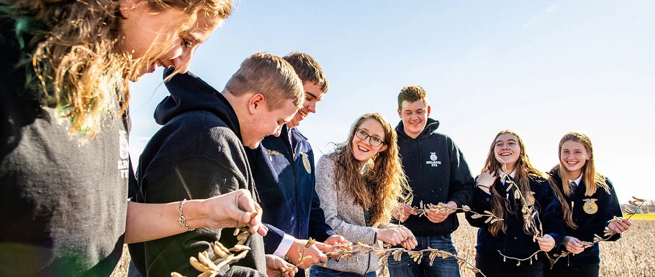 A teacher with a group of students in a bean field