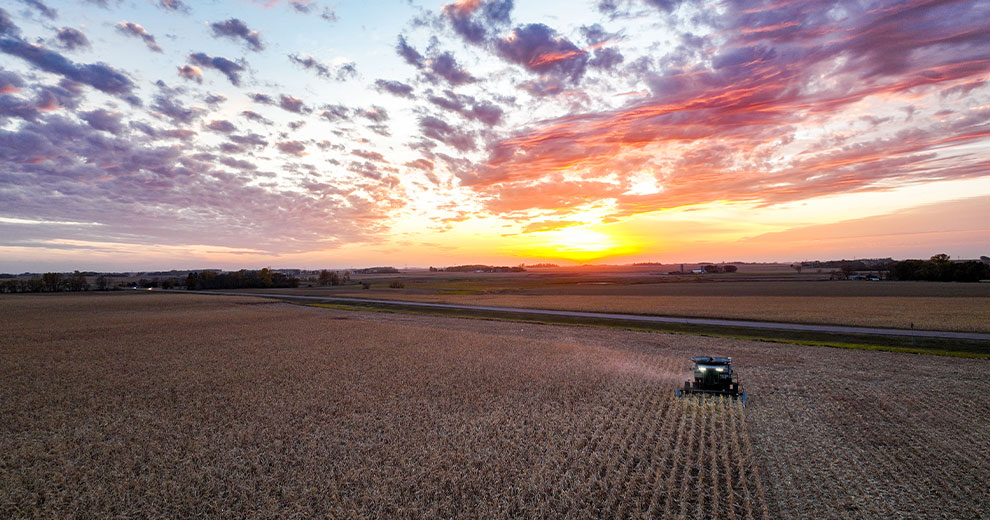 A combine harvesting in a field at sunset.