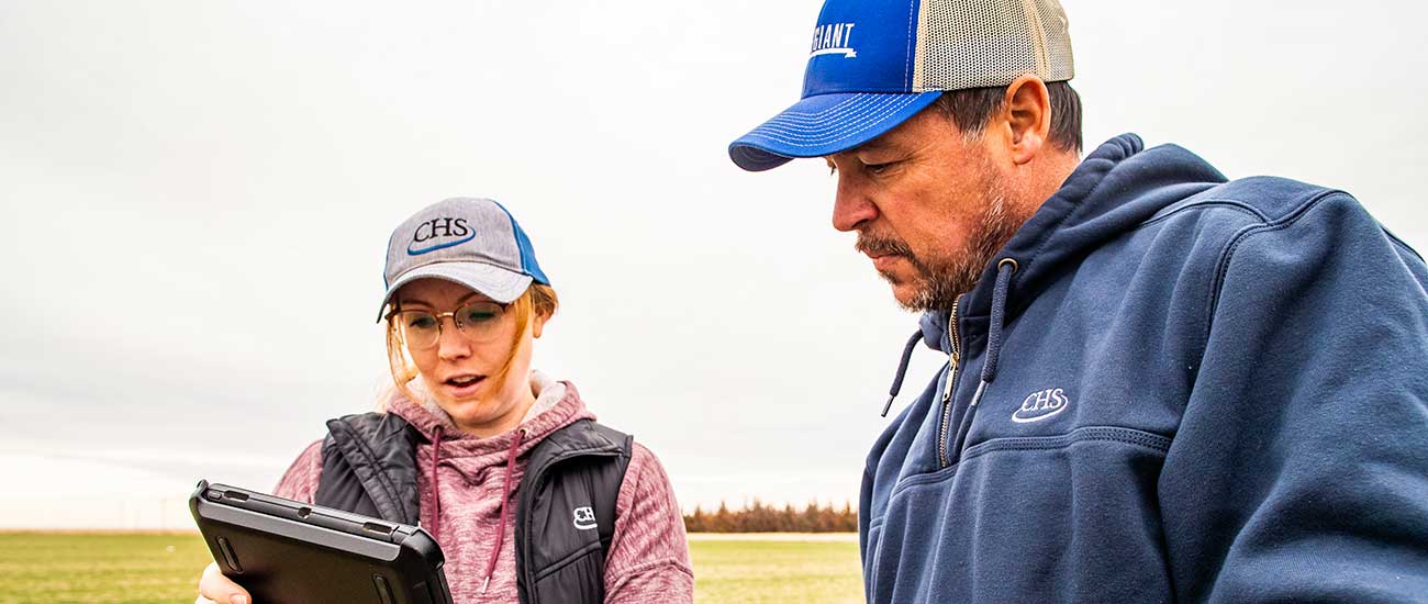 man with woman holding tablet in field
