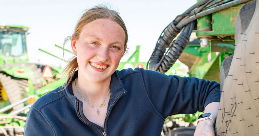 Young woman leaning on tractor tire