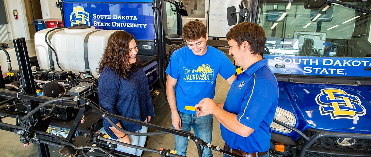 SDSU students and instructor with branded ag equipment