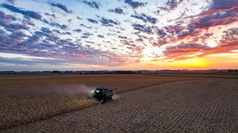 Aerial image of a combine in a field at sunset.