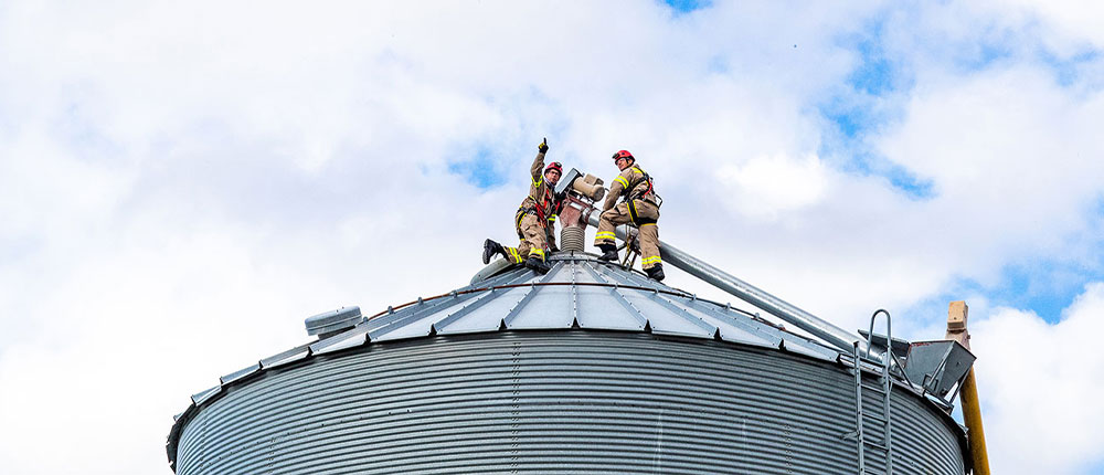 Firefighters working on top of a grain bin