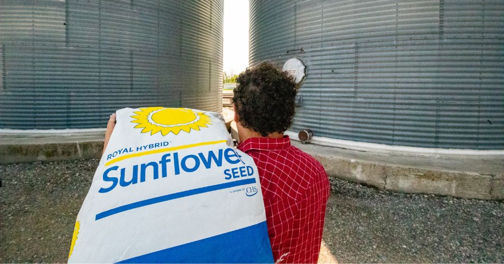 A man carrying a sunflower seed bag over his shoulder.