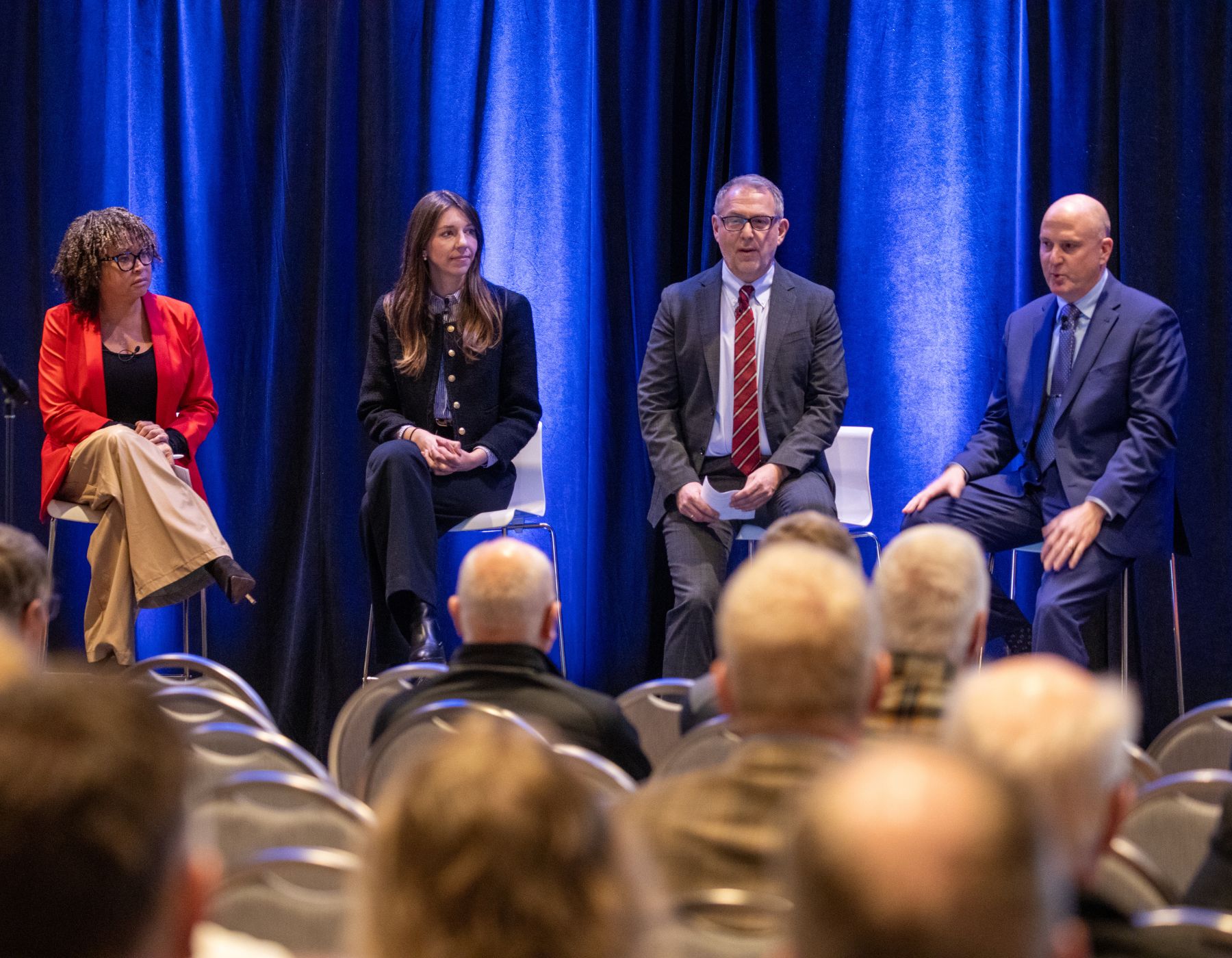 Four people sitting at chairs on a panel.