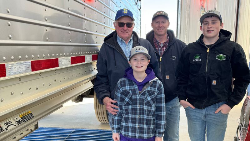 Four people by semi-trailer in a garage