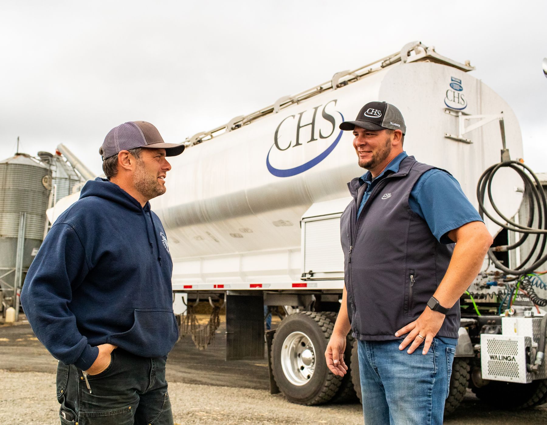 Two men standing near a CHS truck talking